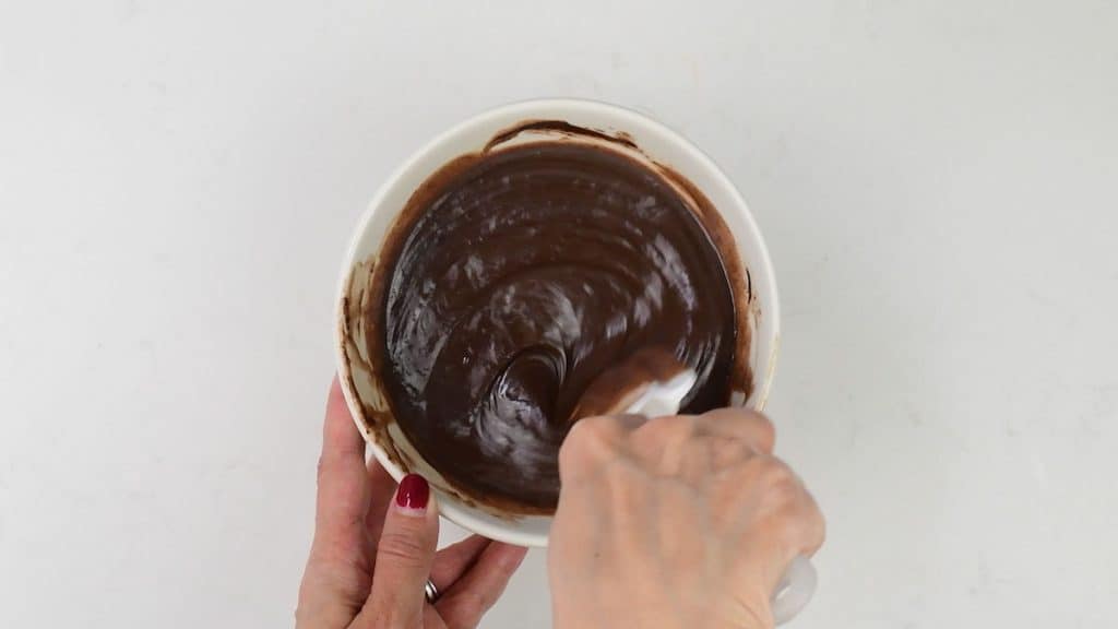 mixing condensed milk and chocolate in a small bowl to make a glaze