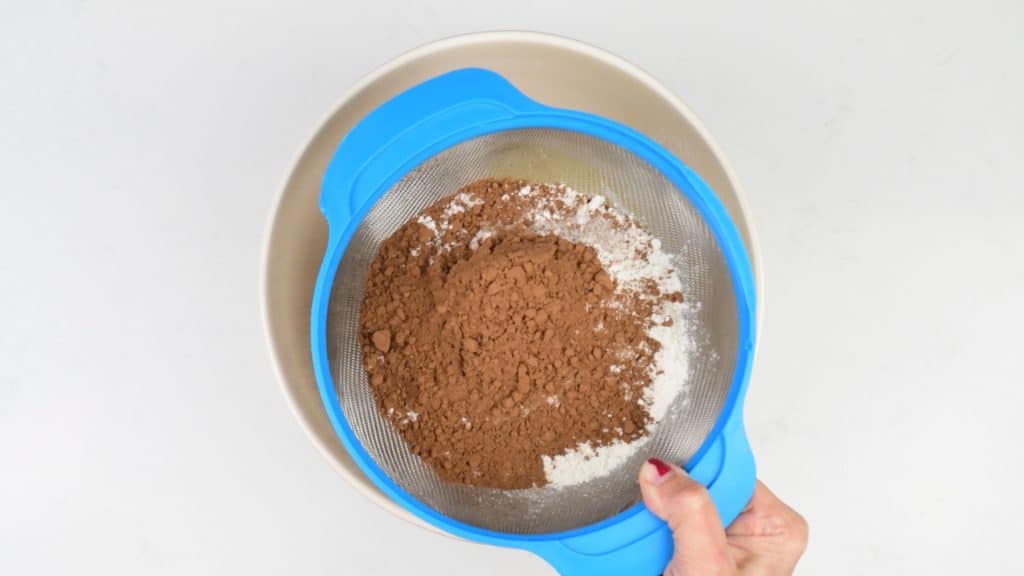 sifting flour, sugar and cocoa over a mixing bowl