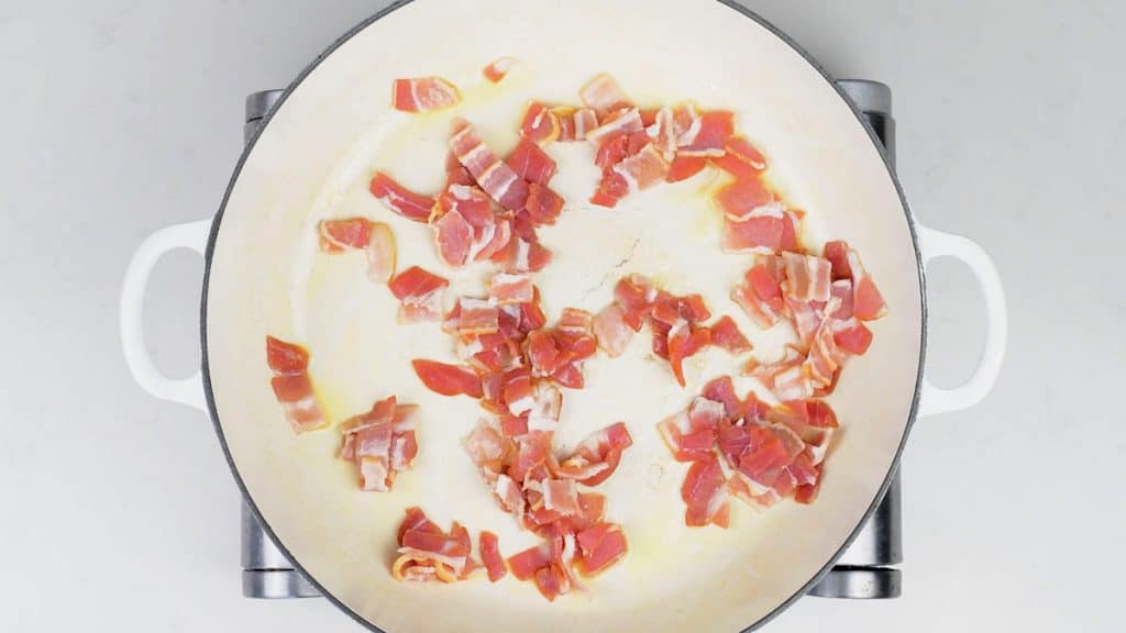 pan frying strips of bacon in a large pan