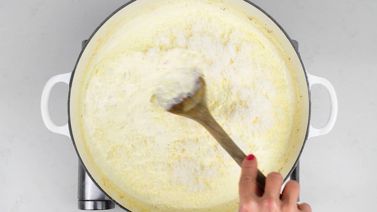 adding freshly grated Parmesan cheese to cream sauce