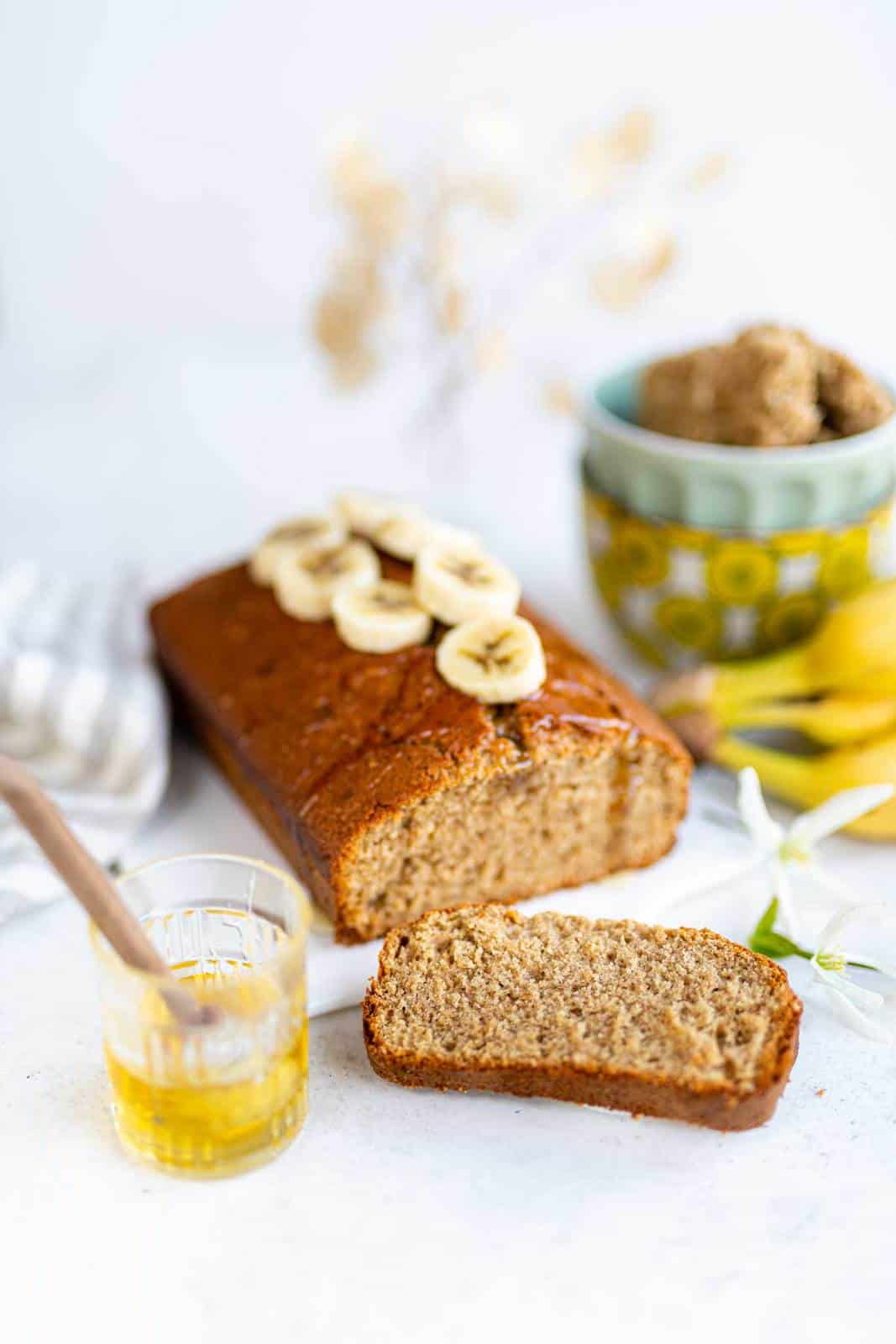 Banana loaf on a white ceramic board with a slice cut out