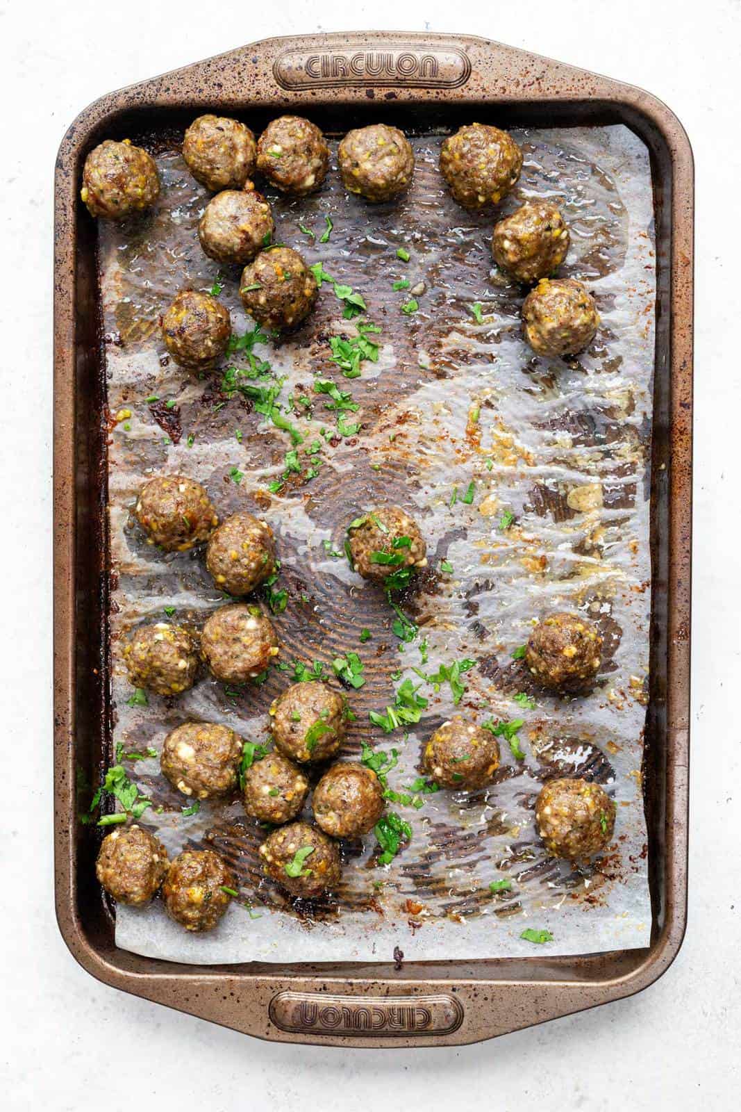 Lamb Meatballs on a baking tray sprinkled with chopped parsley