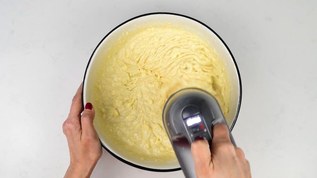 beating cake batter in a bowl with a hand mixer