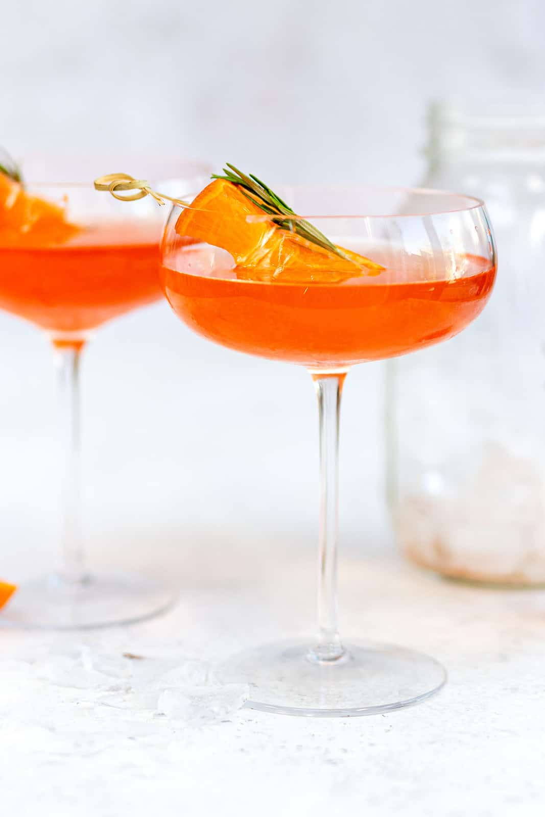 Cocktail with Aperol and tequila served in coupe glasses with orange garnish