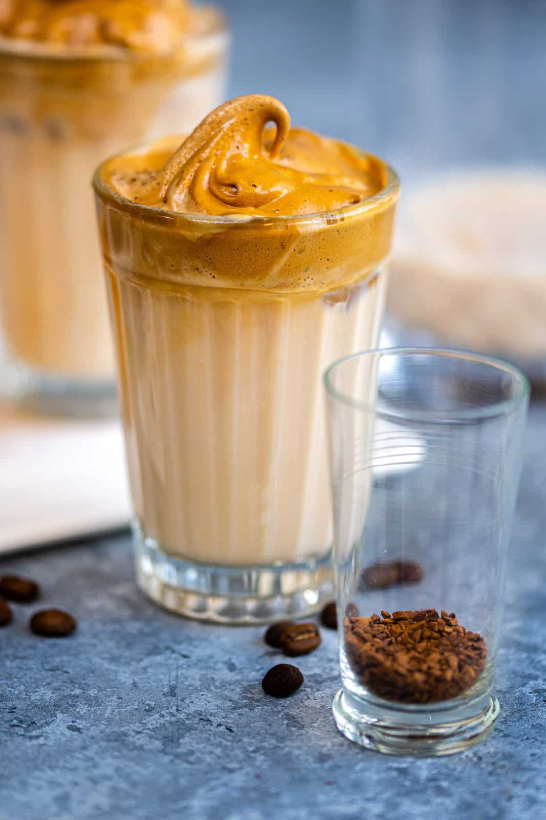 Whipped coffee served over iced milk in a short glass