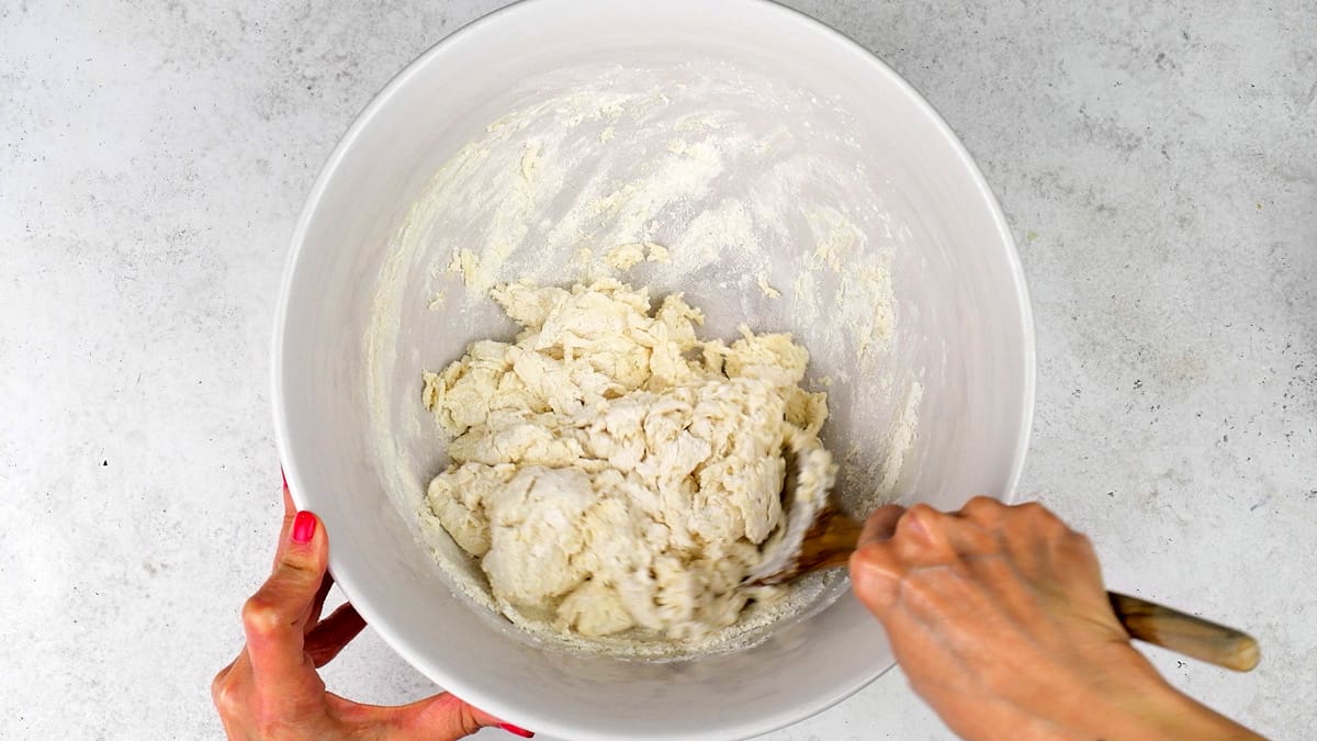 Mixing soda bread dough in a mixing bowl using a wooden spoon