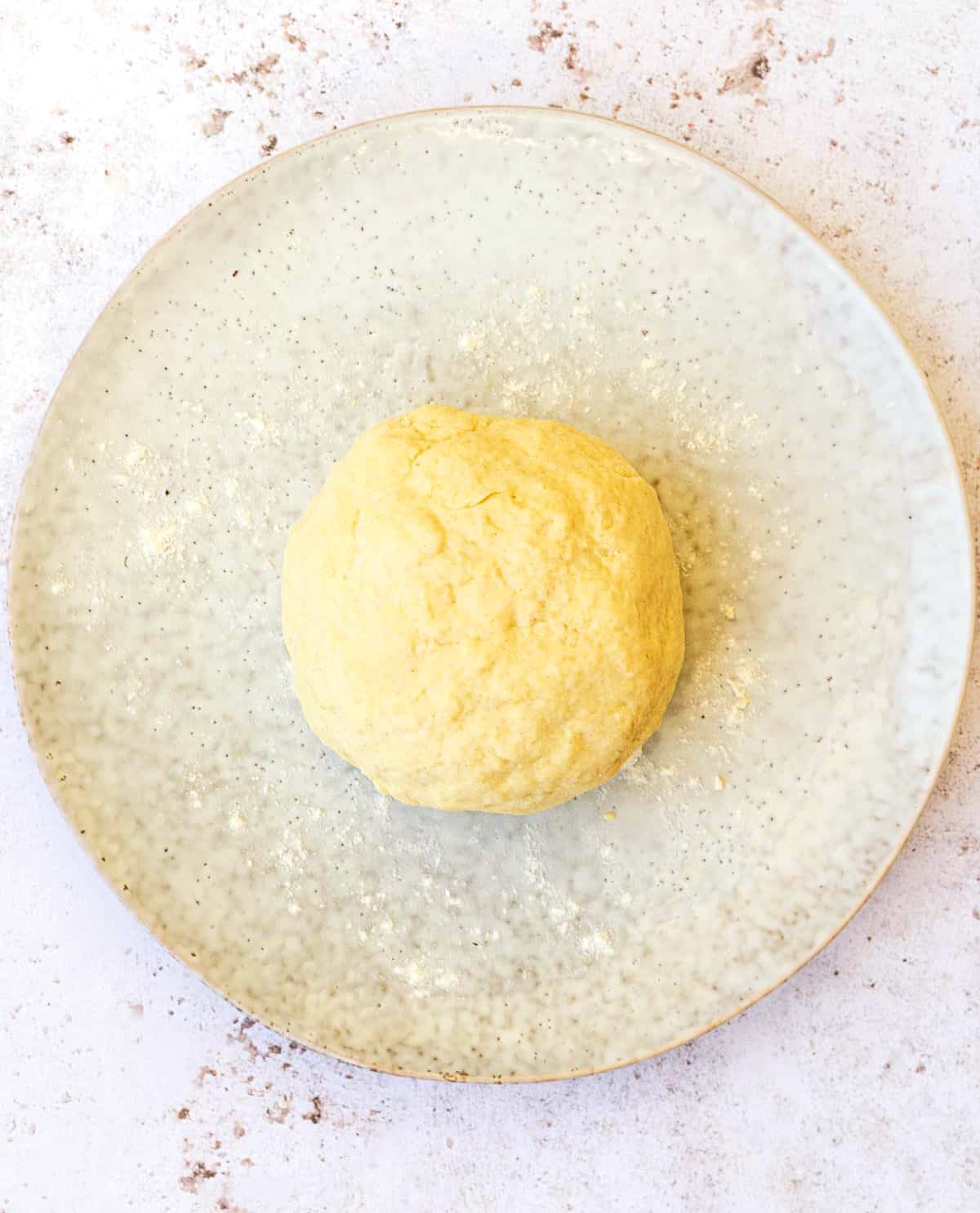 Ball of yeast free quick pizza dough on a round plate