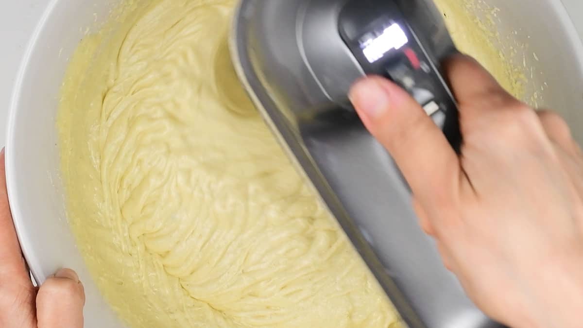Beating vanilla cake batter in a mixing bowl using an electric hand mixer