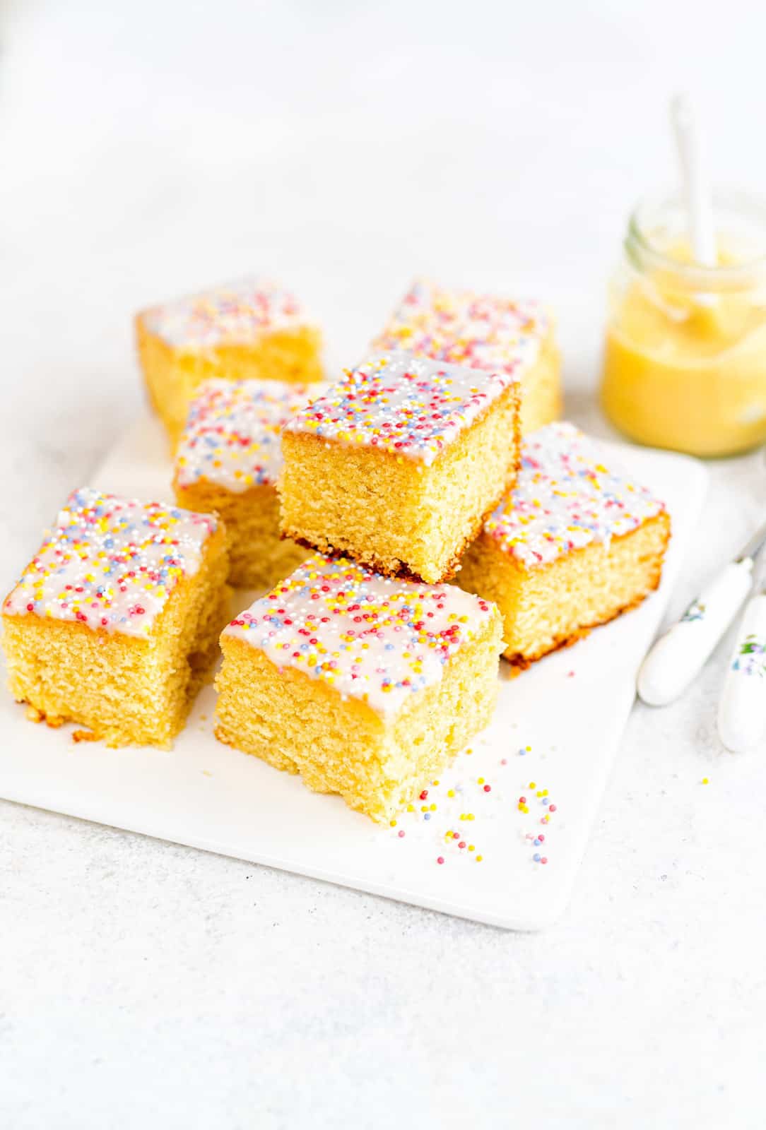 School dinner cake cut into squares covered in white icing and sprinkles