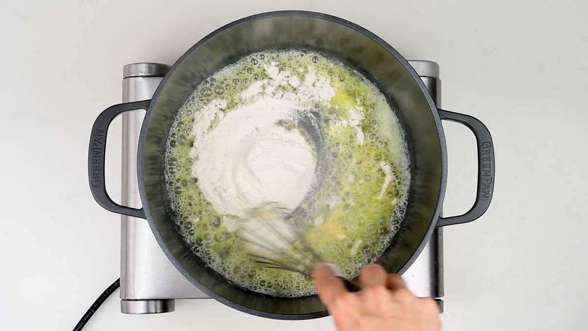 stirring flour into melted butter to make a roux for cheese sauce