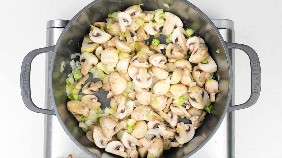 pan frying leeks and mushrooms in a pot