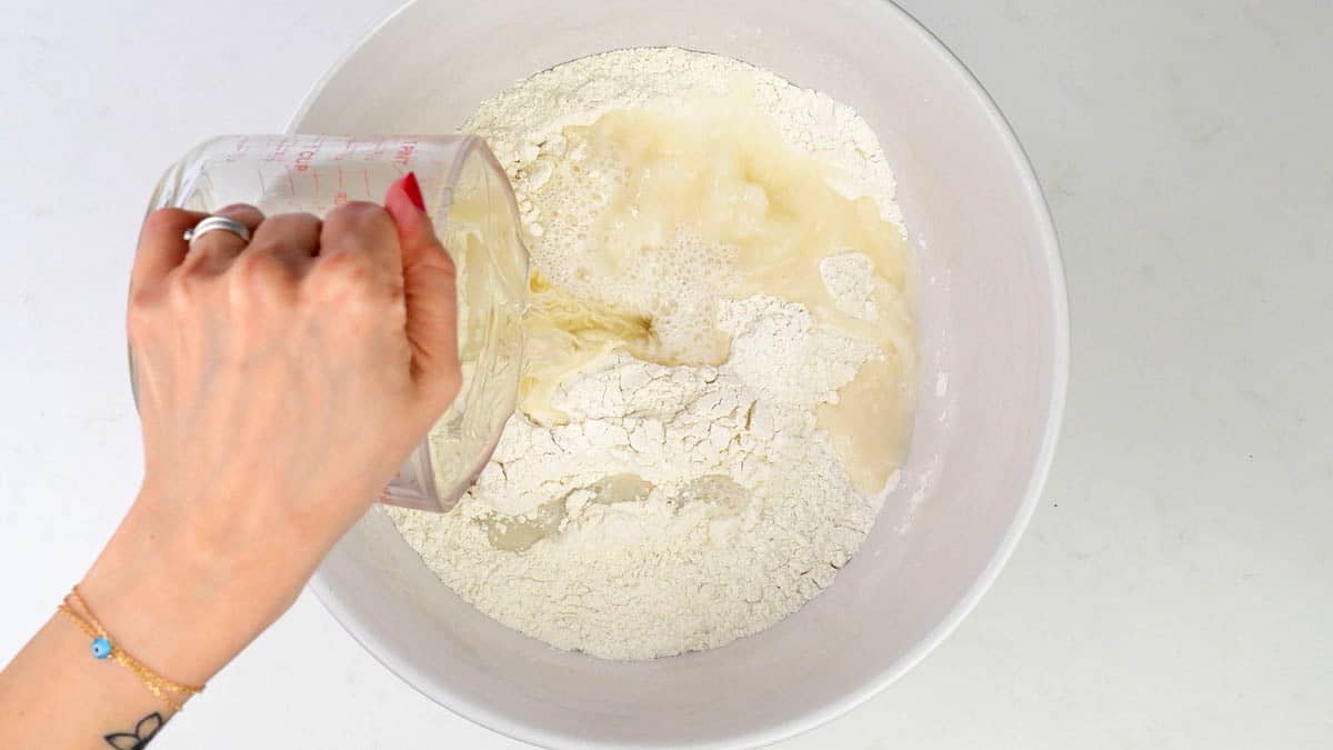 adding water to flour and yeast to make bread dough