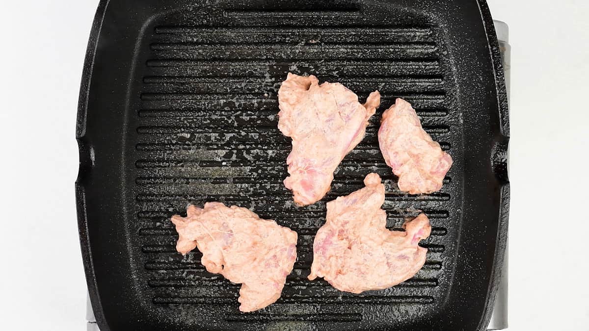 pan frying marinated chicken tikka pieces in a griddle pan