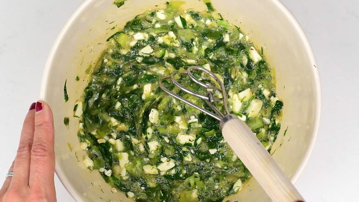 combining eggs, spinach, feta and herbs in a bowl