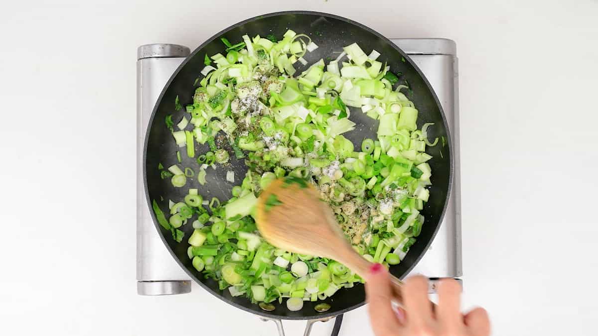 pan frying leeks and spring onions in a pan