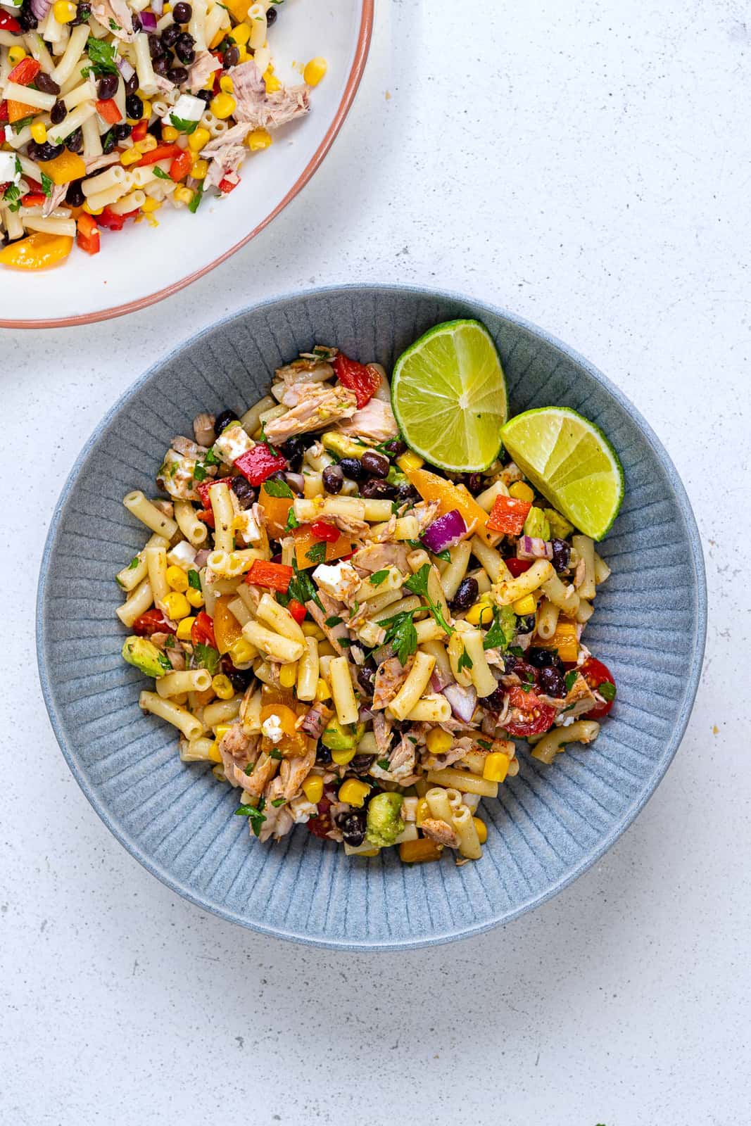 Healthy Tuna pasta salad in a grey bowl with limes on the side