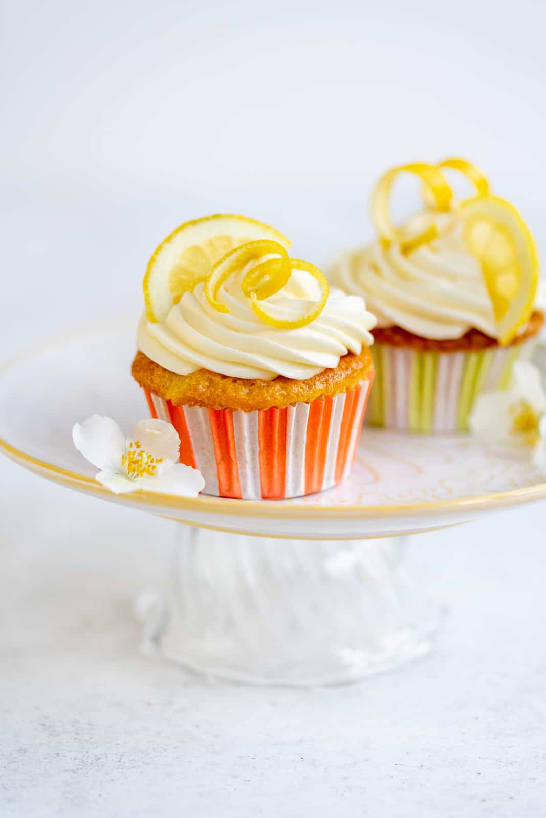 Lemon drizzle cupcakes with cream cheese frosting on a small cake stand