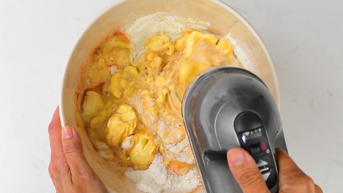 beating batter for banana cake in a mixing bowl using a hand mixer