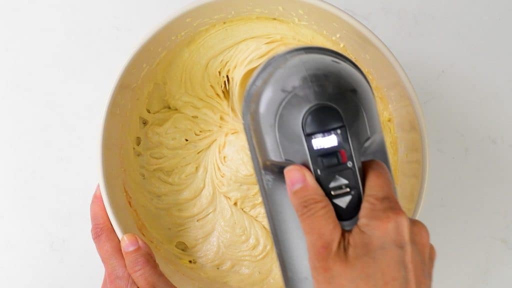beating cake batter in a mixing bowl with an electric hand mixer