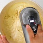 beating cake batter in a mixing bowl with an electric hand mixer