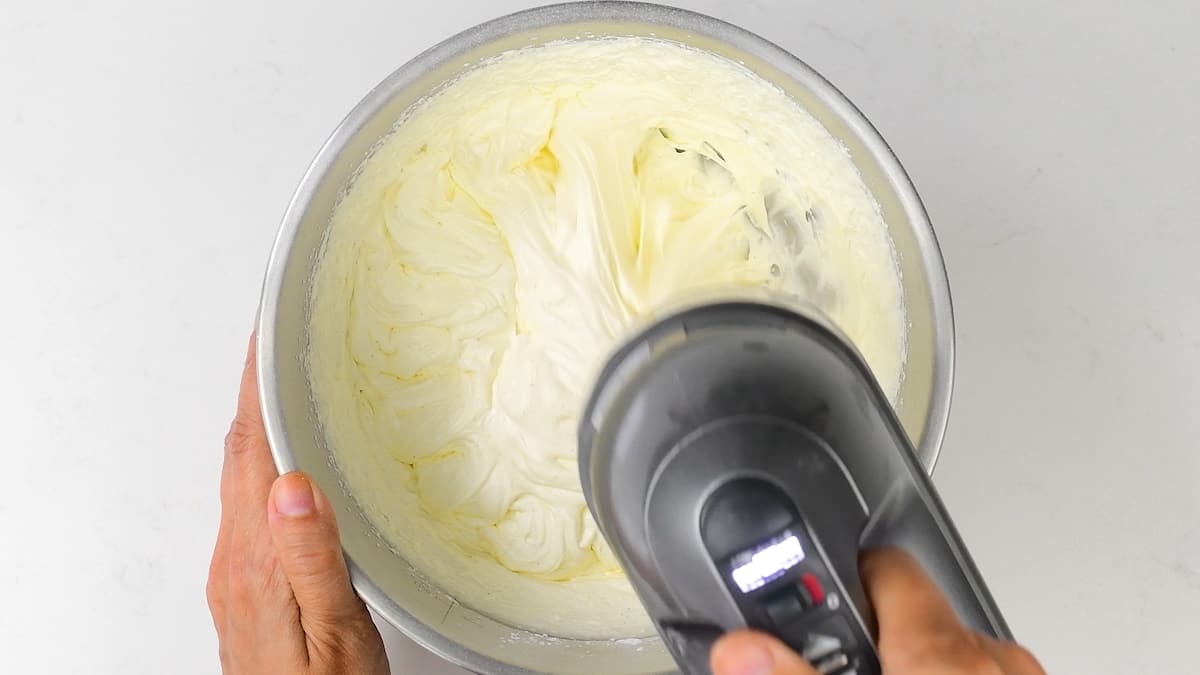 Whipping cream in a bowl with a hand mixer