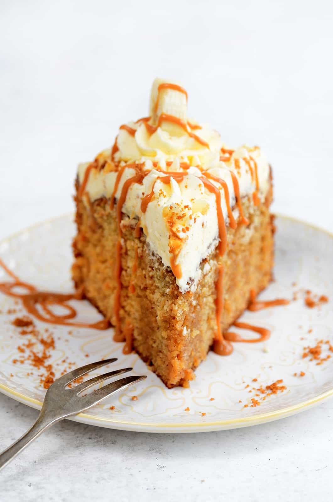 Slice of Banoffee Cake topped with whipped cream and drizzled with caramel