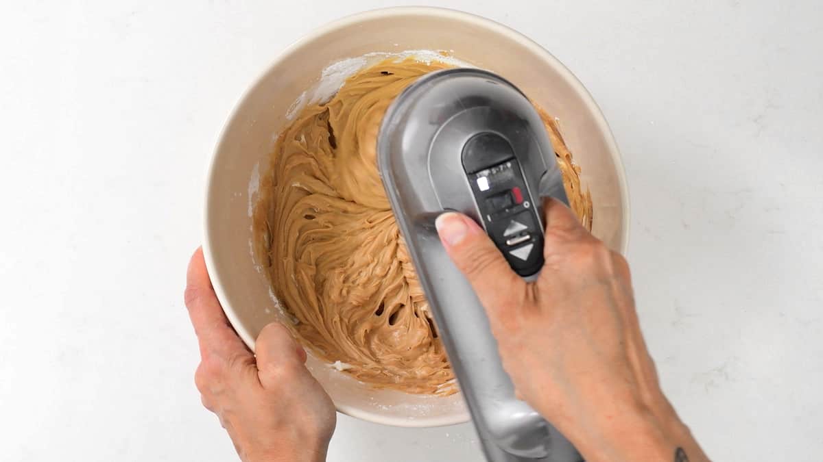 beating Lotus Biscoff spread, mascarpone cheese, icing sugar in a bowl using a hand mixer