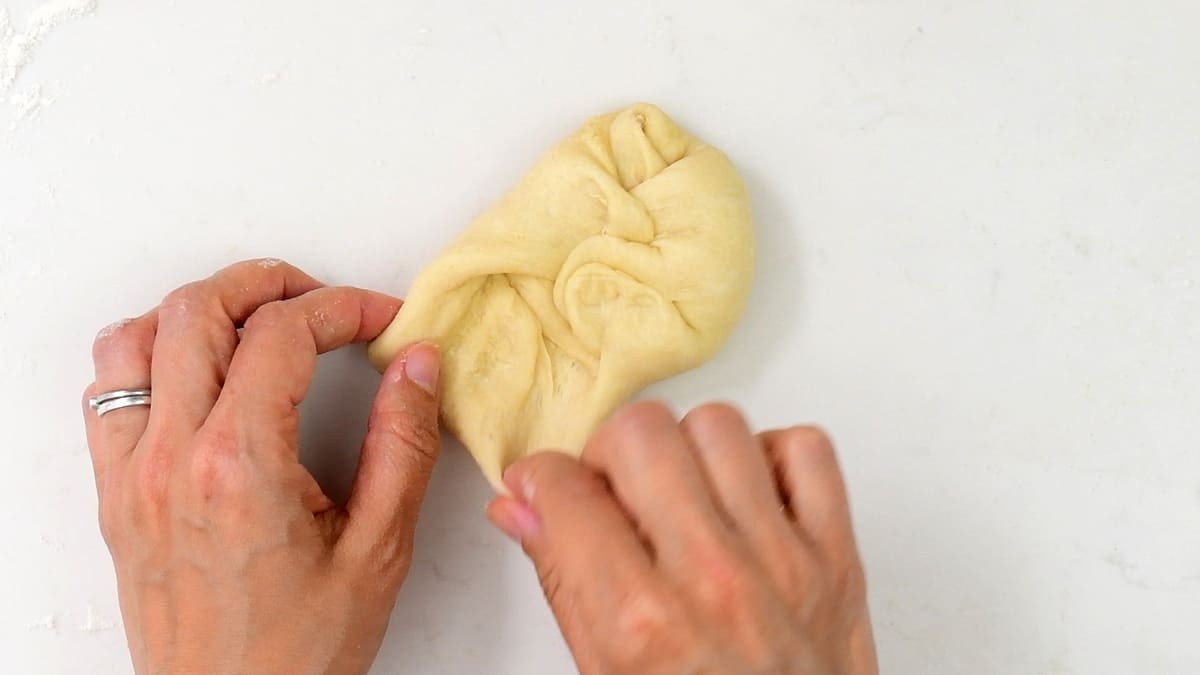 tucking the edges of dough inwards to make a roll