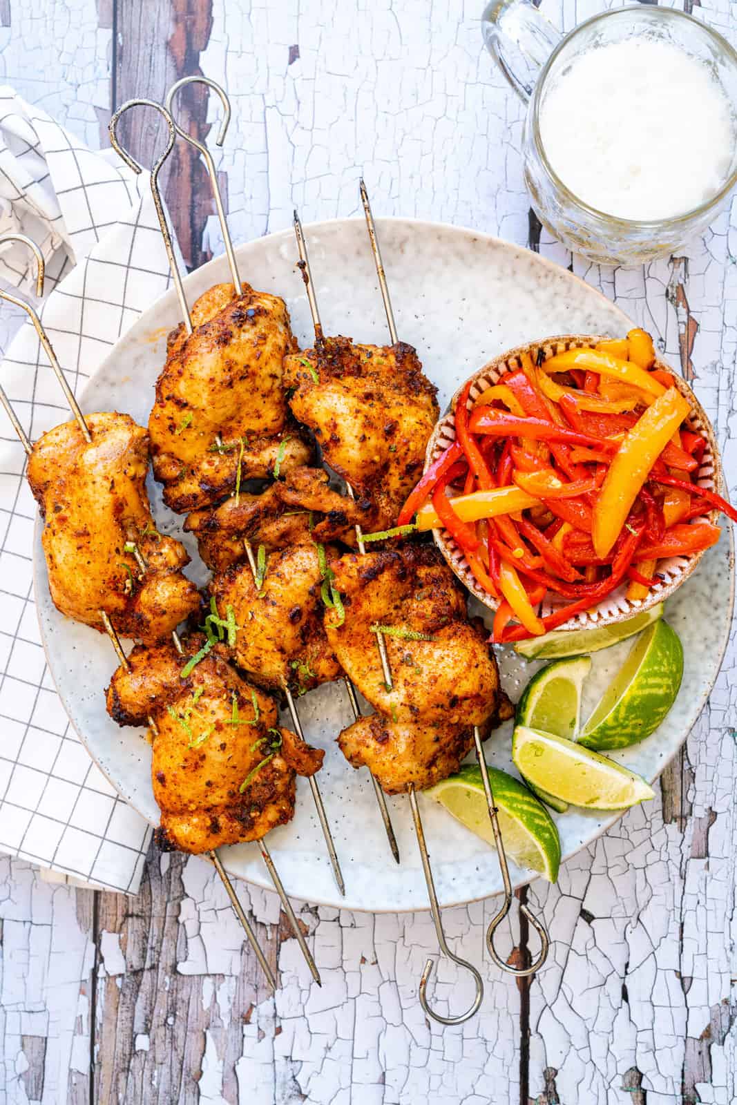 Peri Peri chicken thighs served with colourful sliced peppers and lime wedges