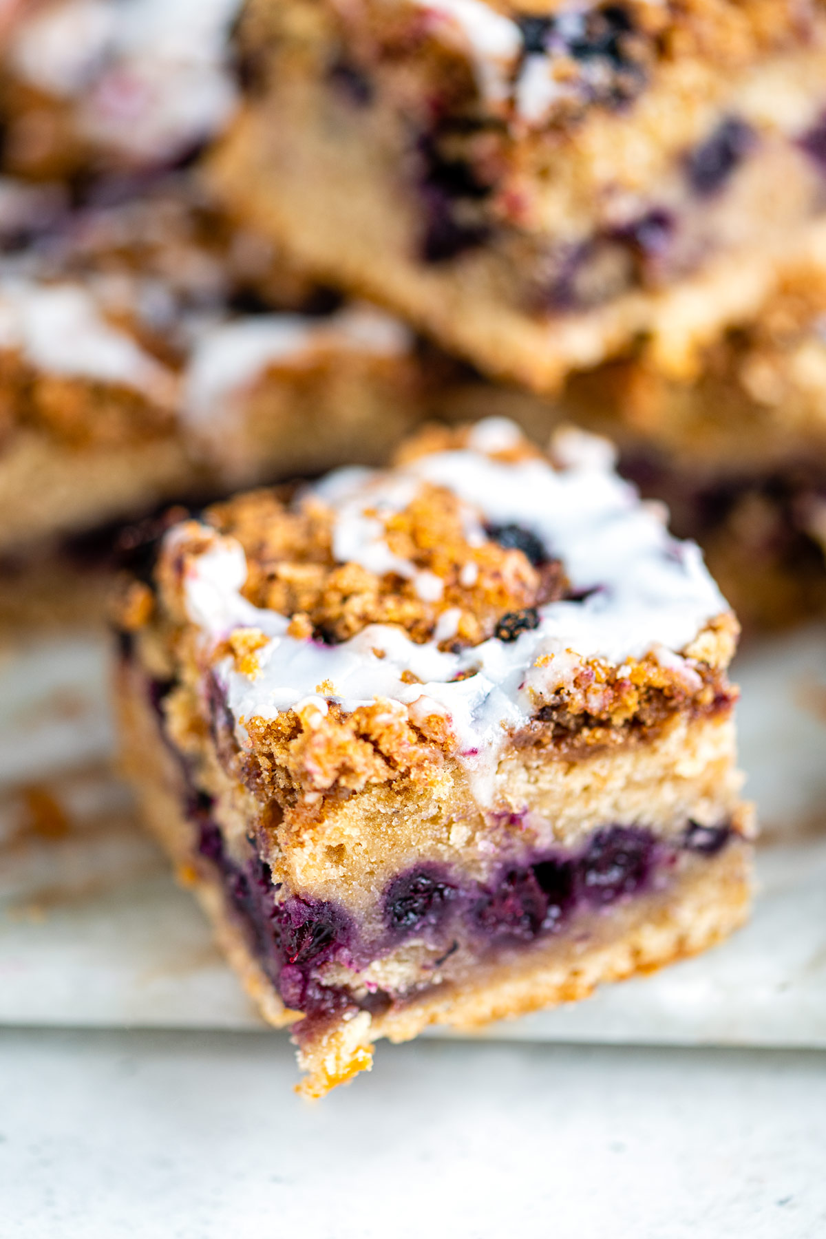 Close up on a square of sourdough blueberry crumb cake with streusel topping and simple glaze