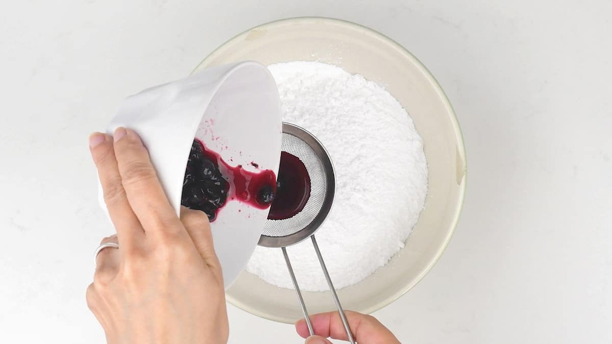 Making pink cake icing by adding blueberry juice to icing sugar