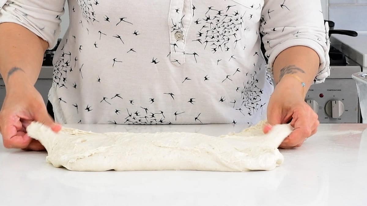 gently stretching sourdough bread dough to form a rectangle