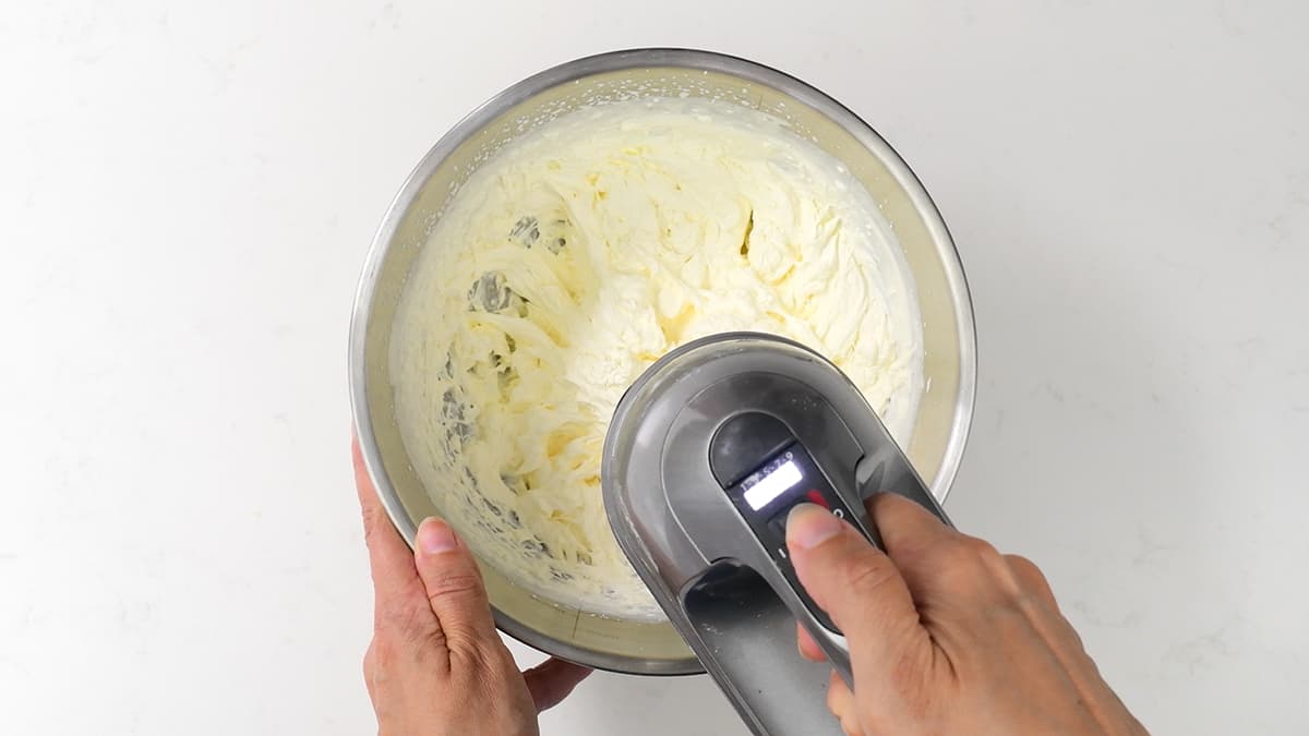 whisking double cream in a metal bowl using hand mixer