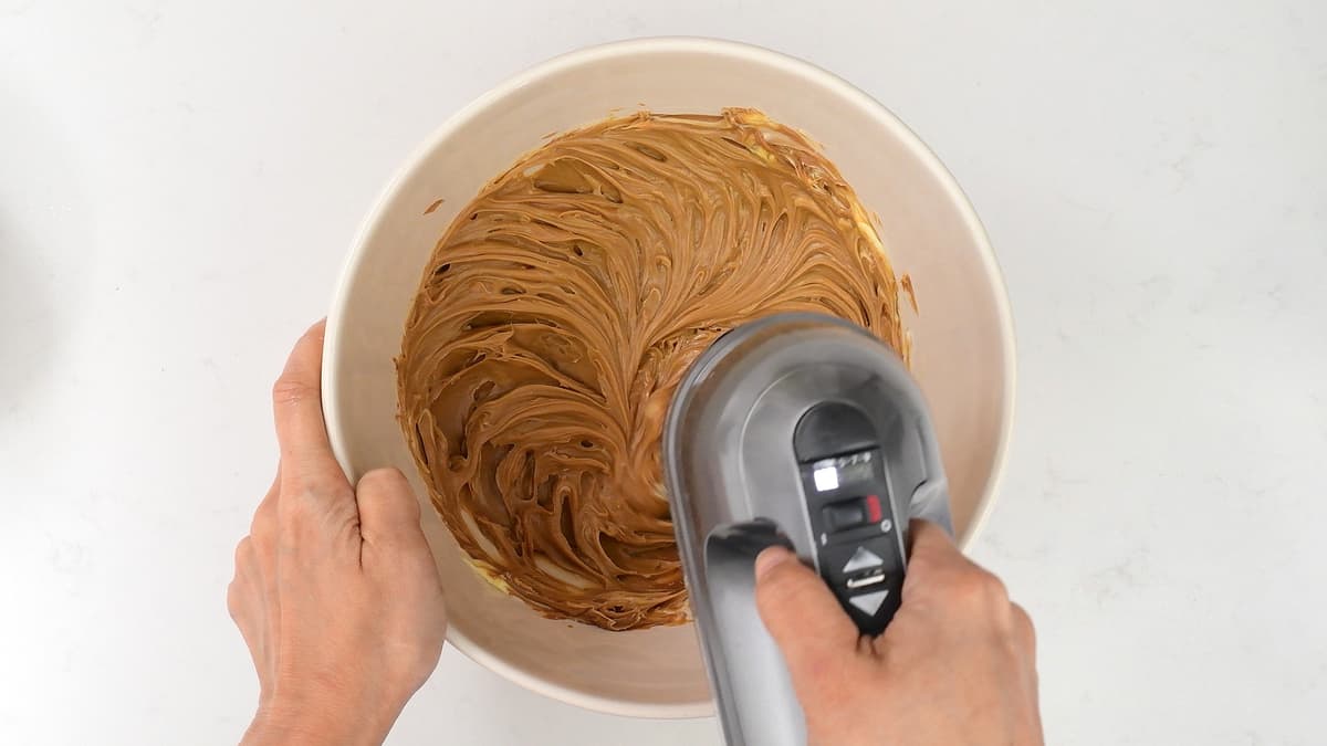 beating Biscoff spread and butter in a bowl using a hand mixer to make buttercream