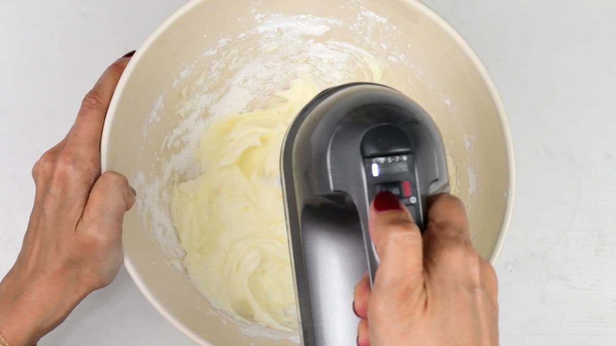 beating cream cheese and icing sugar in a bowl using a hand mixer