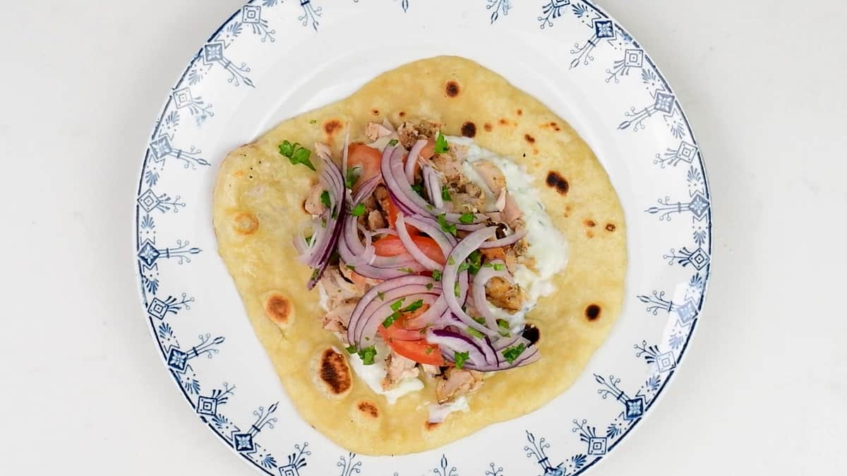 chicken gyros served in a pita bread with tzatziki sauce, tomato and sliced onions