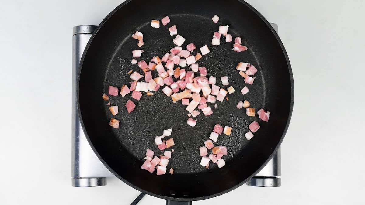 pan frying bacon cubes in a non stick pan