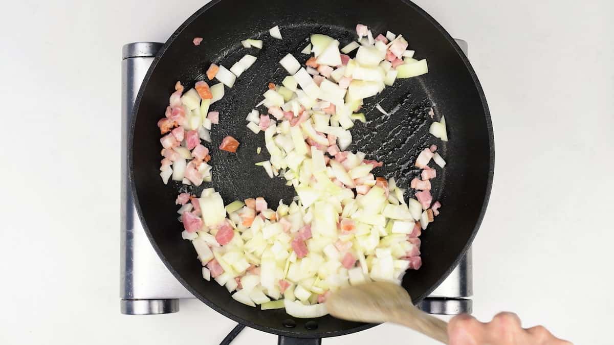 pan frying diced onion and bacon in a pan