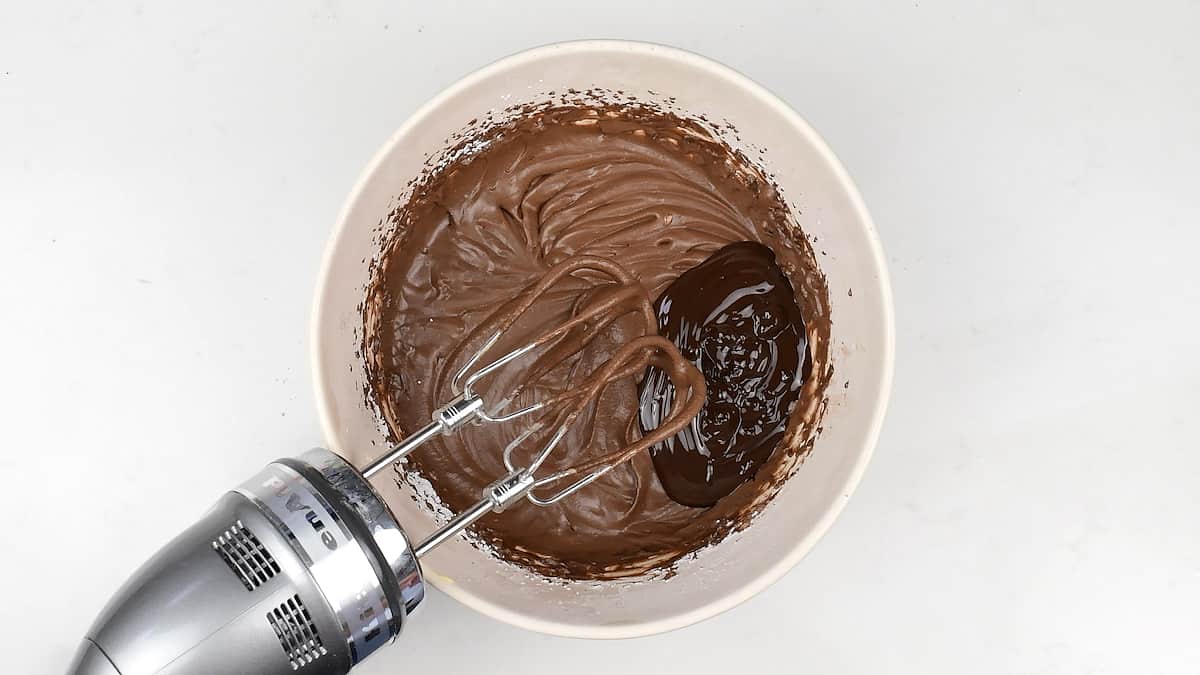 Making chocolate frosting in a bowl using a hand mixer
