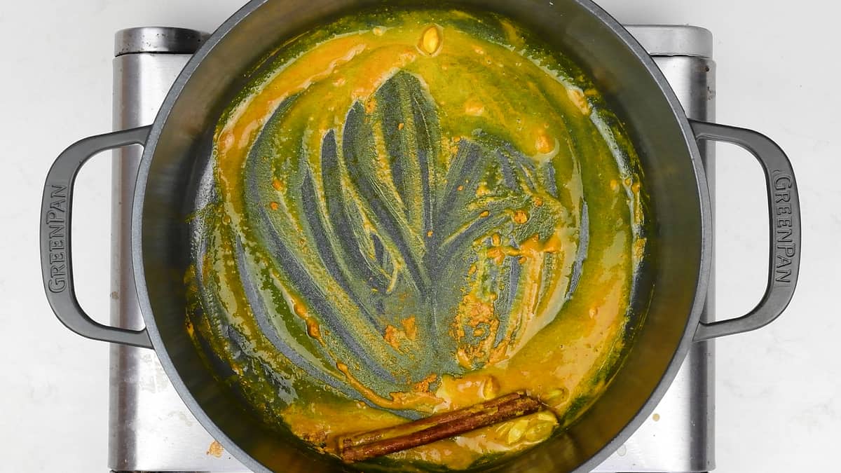 cooking turmeric, cardamom pods and cinnamon stick in butter