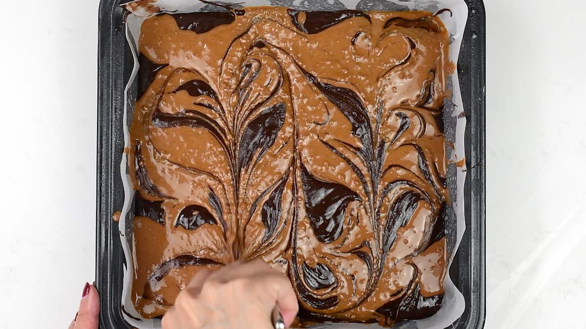 swirling Biscoff spread into brownie batter using a knife