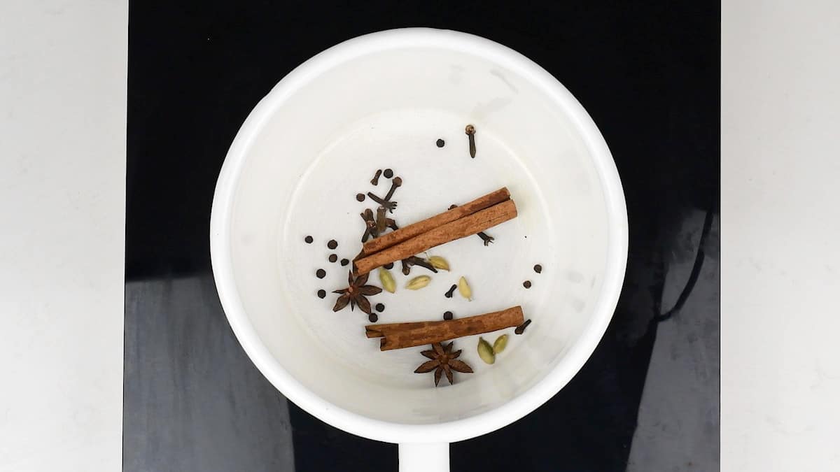 toasting cinnamon sticks, cardamom pods, peppercorns, cloves, star anise in a saucepan for chai tea