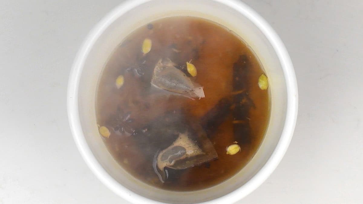 steeping tea bags  in hot water and spices to make chai masala