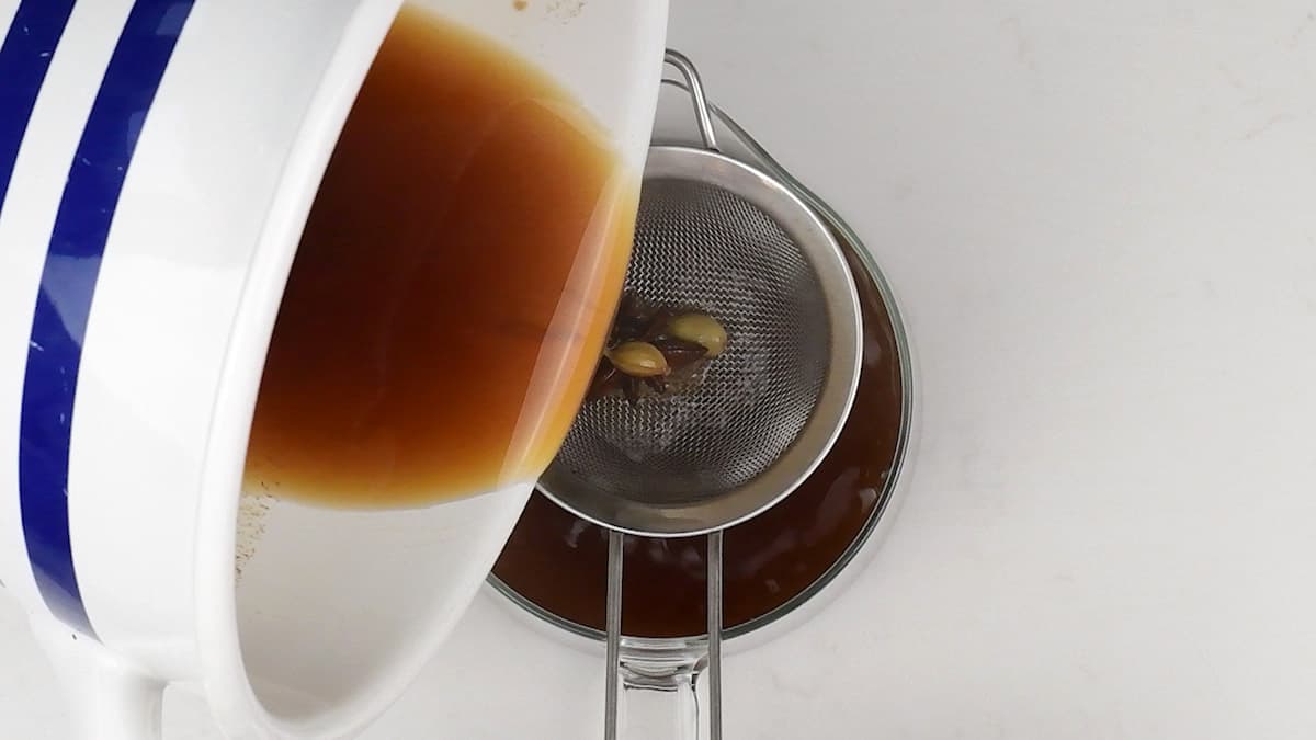 straining chai tea into a teapot