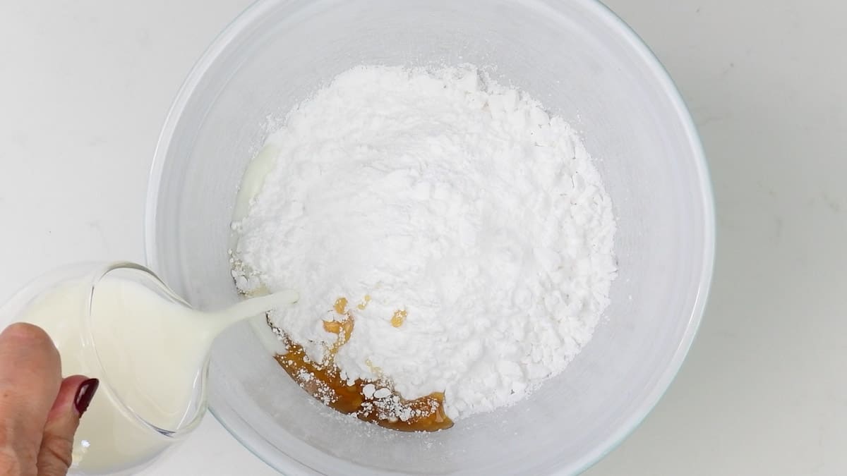 mixing icing sugar, vanilla extract and milk in a bowl to make cake glaze