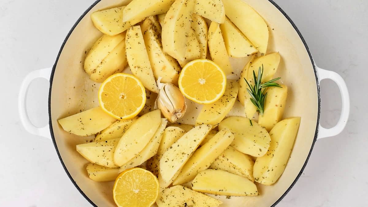 potato wedges tossed with olive oil, lemon, rosemary and oregano in a pan