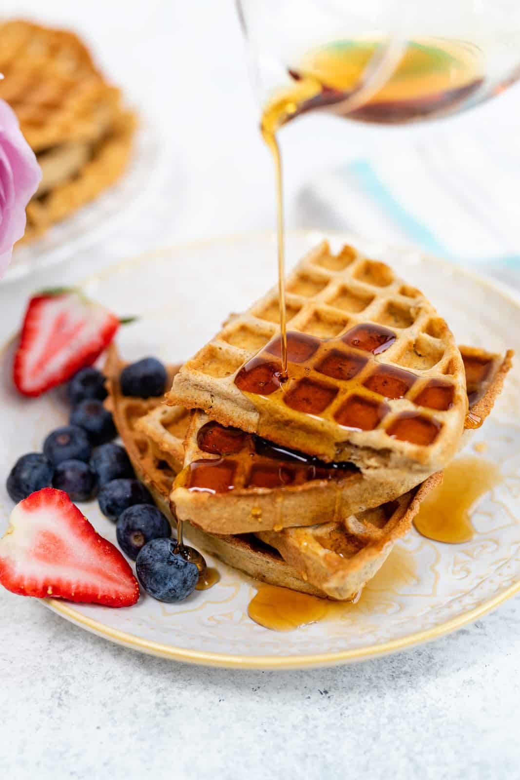 drizzling maple syrup over a stack of slimming world waffles