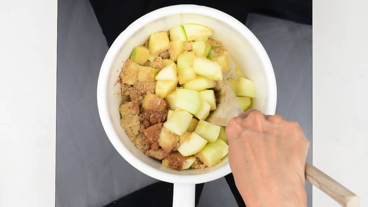 Stirring apples, sugar and cinnamon in a saucepan