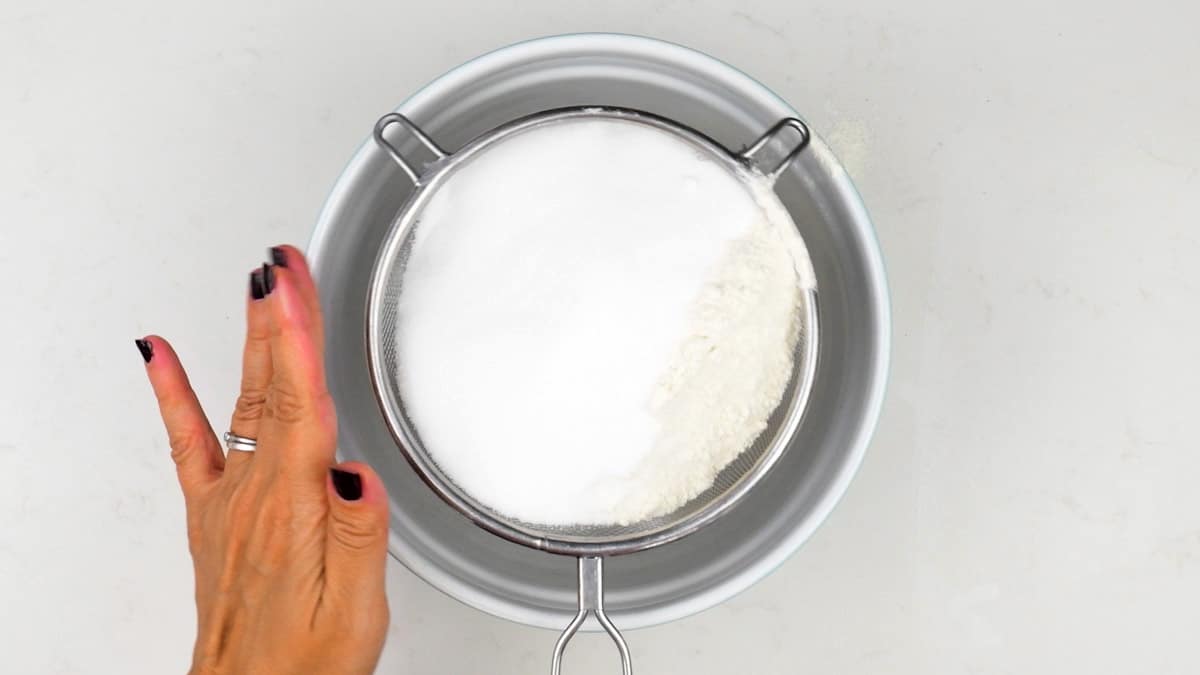 Sifting flour, sugar and baking powder into a mixing bowl