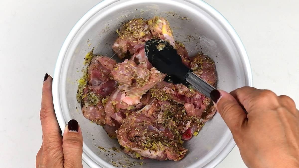 mixing chicken thighs with marinade in a bowl
